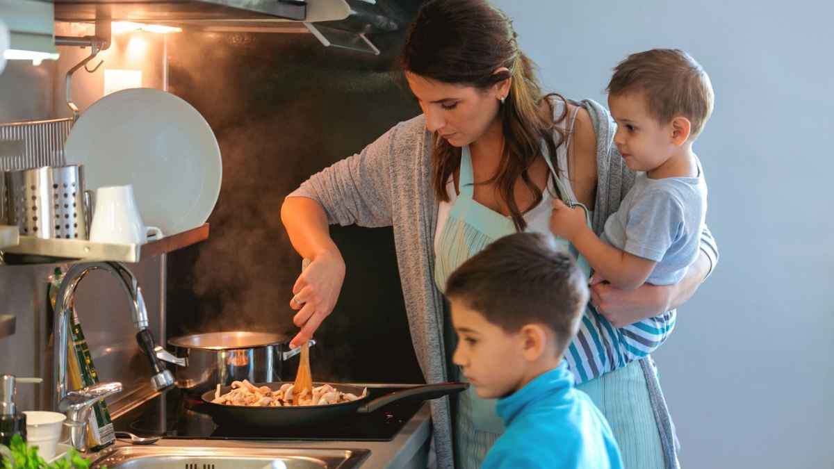 Ama de casa cocinando en su hogar mientras cuida de sus hijos, ejemplo de mujeres sin cotizar que podrán cobrar pensión en 2026