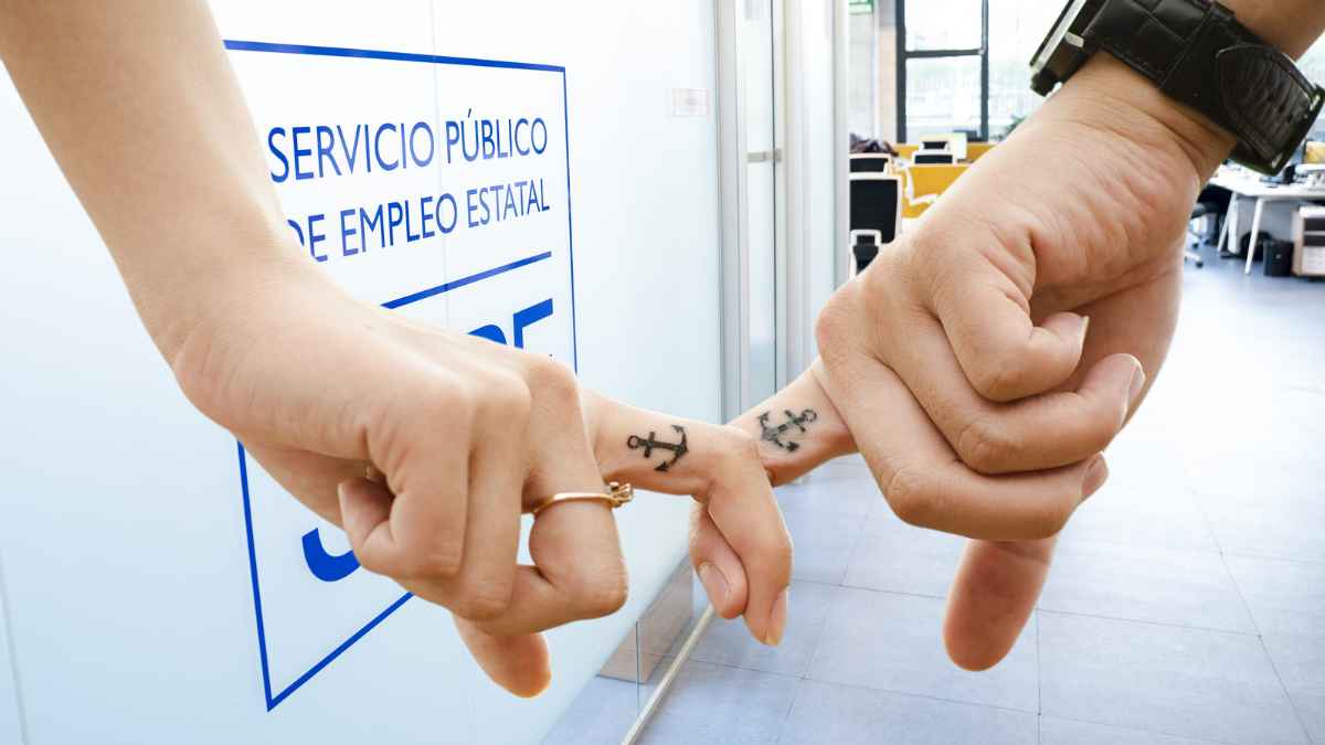 Manos de una pareja frente a una oficina del SEPE tras la sentencia del Supremo sobre el subsidio por desempleo