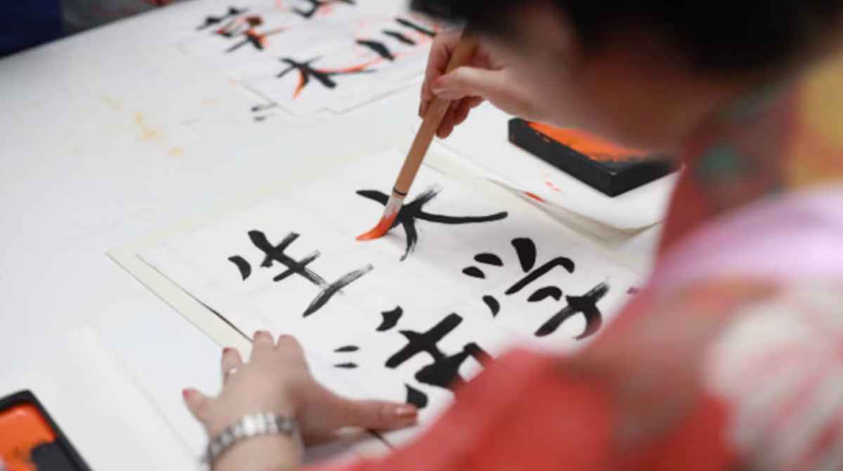 Persona practicando caligrafía japonesa en casa como parte de un curso de japonés gratis