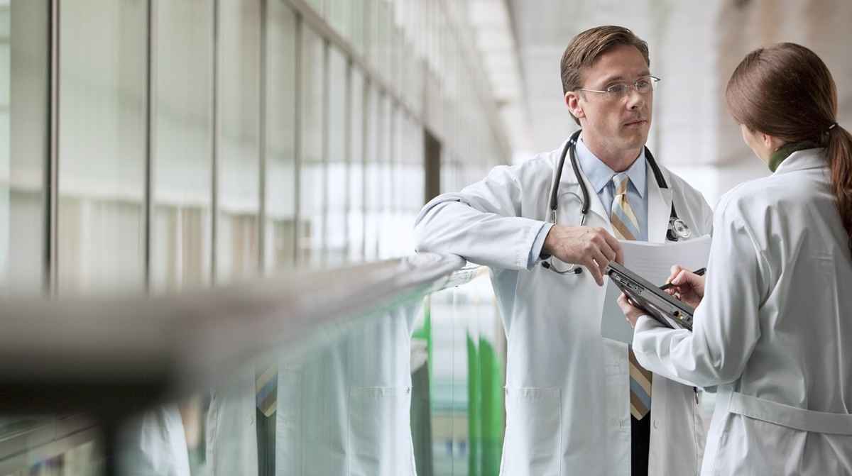 Médico hablando con una compañera en un hospital tras un caso de despido por acoso laboral y sexual