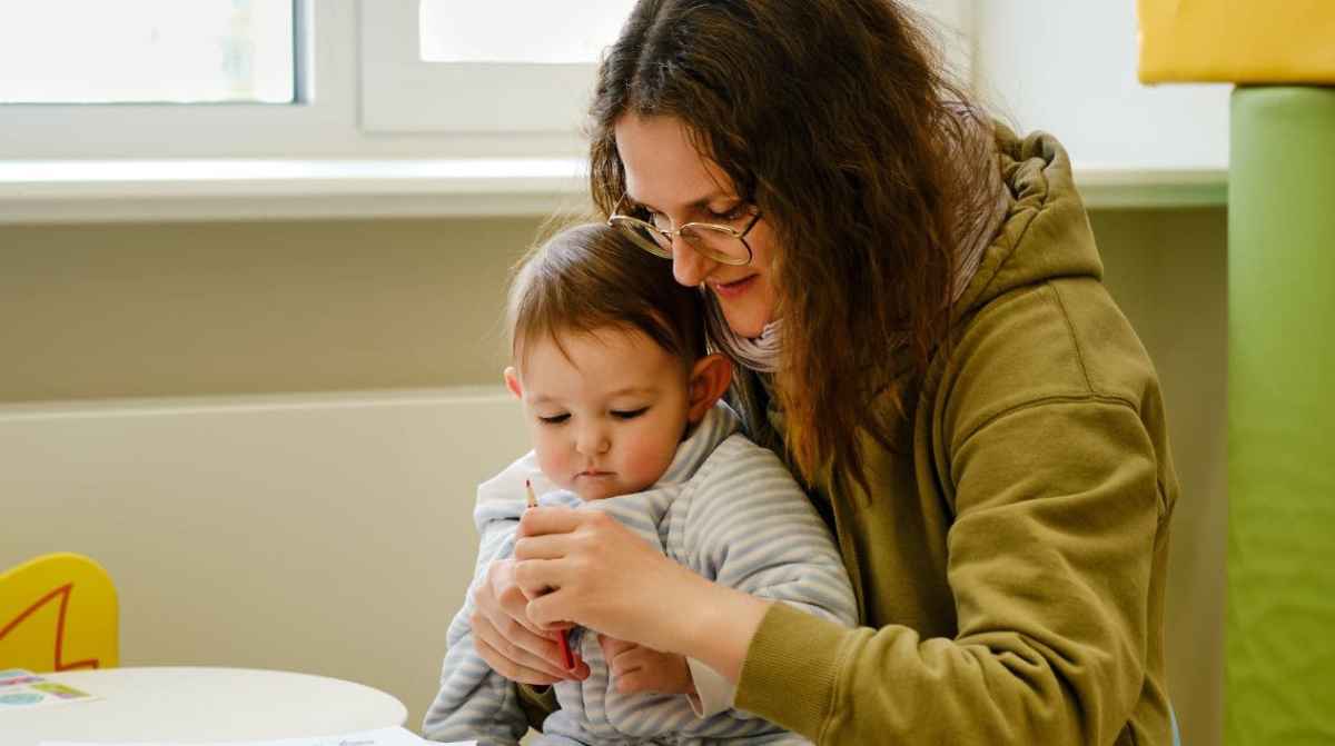 Madre con su hijo menor de tres años, beneficiaria de la prestación universal por crianza de 200 euros al mes