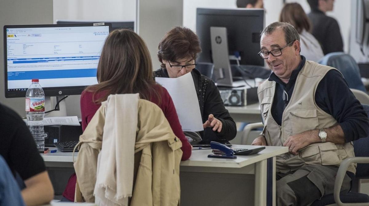 jubilados realizando la declaracion de la renta en una oficina con asesor de hacienda
