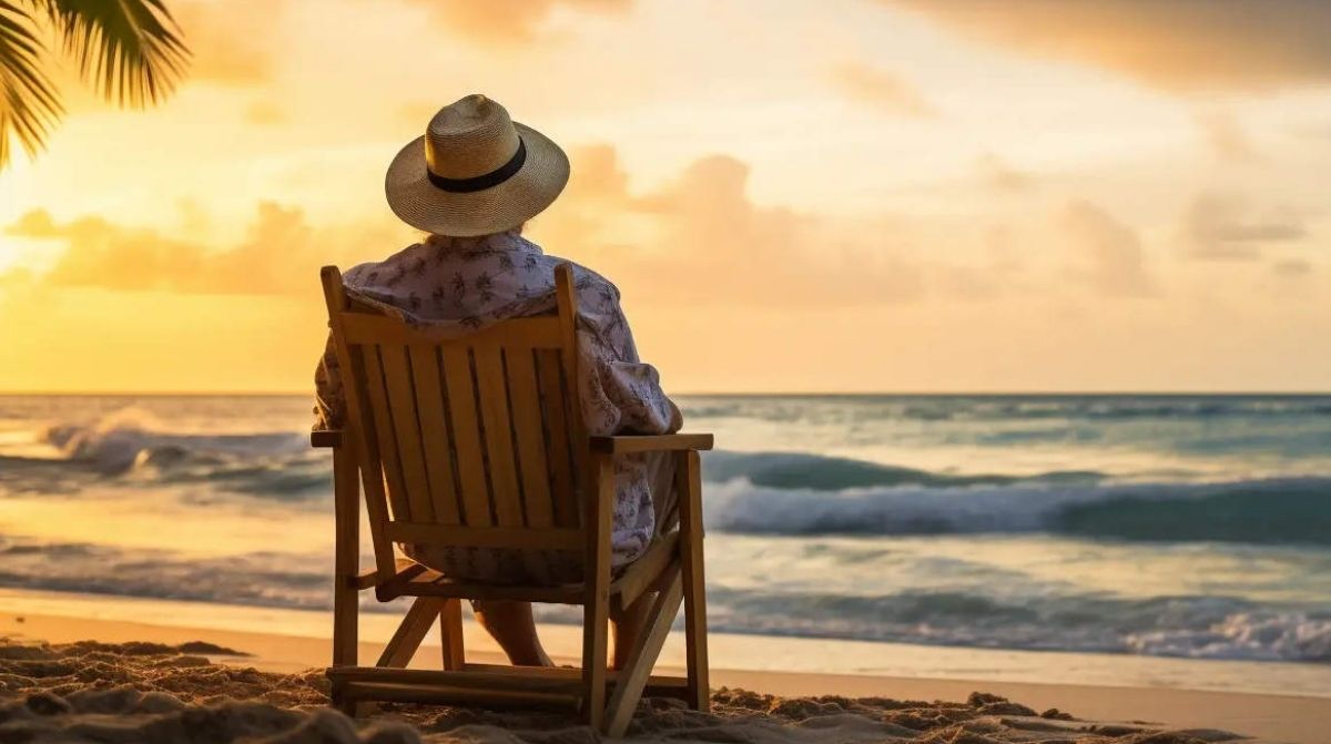 Persona mayor sentada en la playa al atardecer tras jubilarse anticipadamente