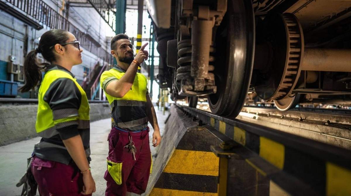 Técnicos de mantenimiento de Renfe revisando tren en taller ferroviario en España