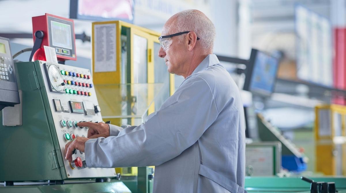 Trabajador mayor operando maquinaria en una fábrica tras retrasar la jubilación para aumentar su pensión un 4%