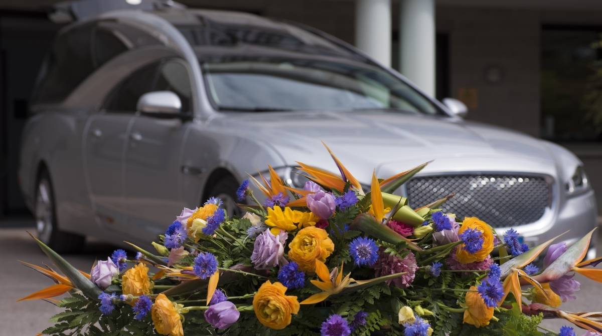 Coche fúnebre con flores en un sepelio relacionado con la ayuda de 46,50 euros de la Seguridad Social por auxilio por defunción