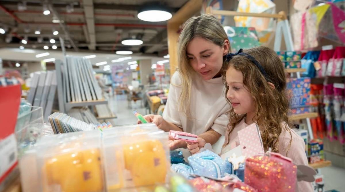 madre y niña comprando material escolar con ayuda de 120 euros para gastos educativos