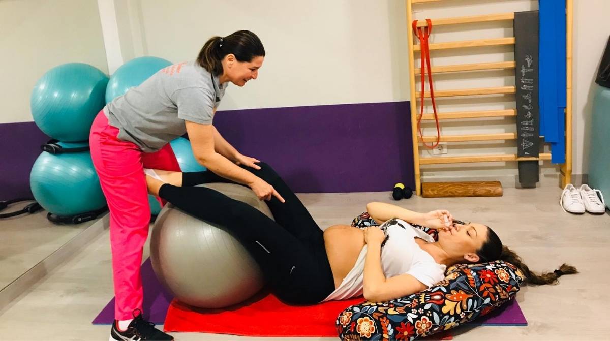 Trabajadora embarazada realizando ejercicios de preparación al parto durante una sesión prenatal
