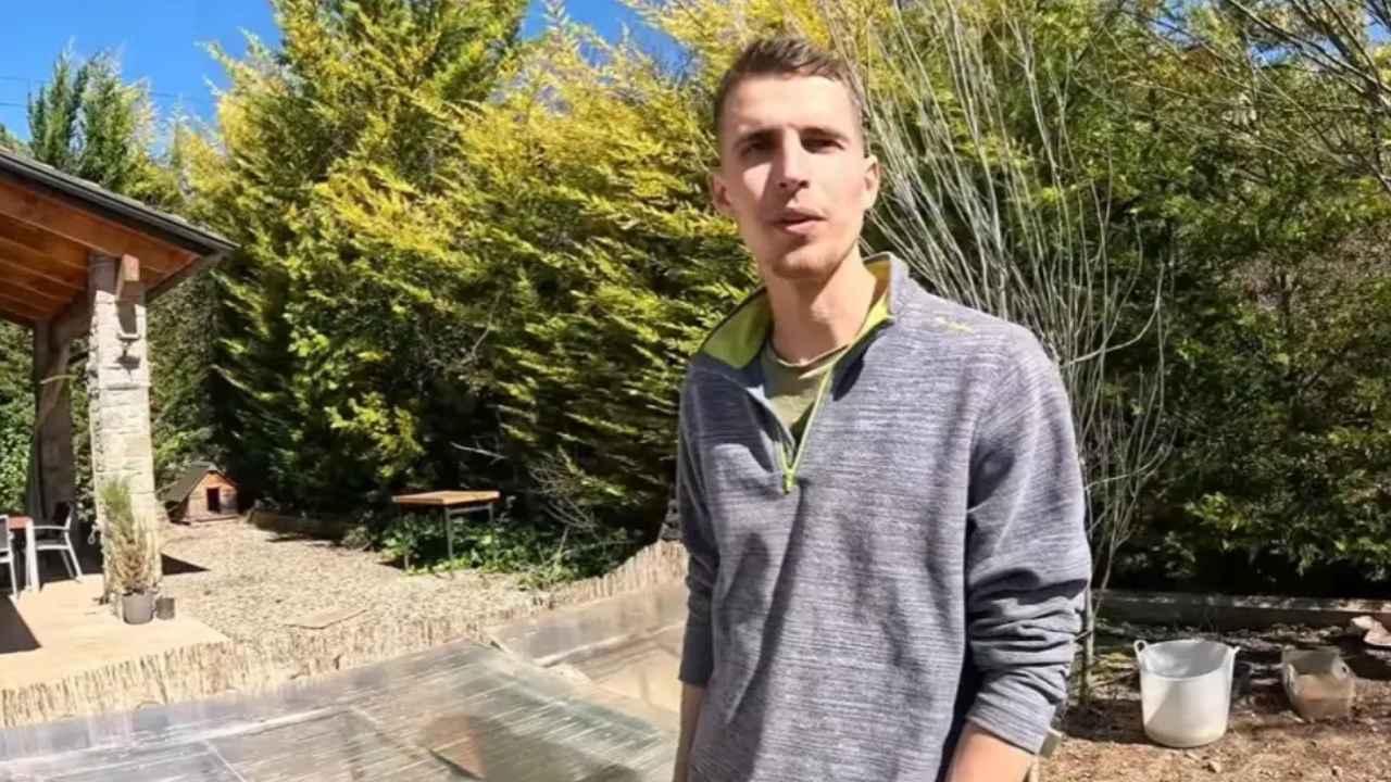 Infoemplea2 1 Arnau sostiene unas astas frente a una vivienda rural de piedra y madera.