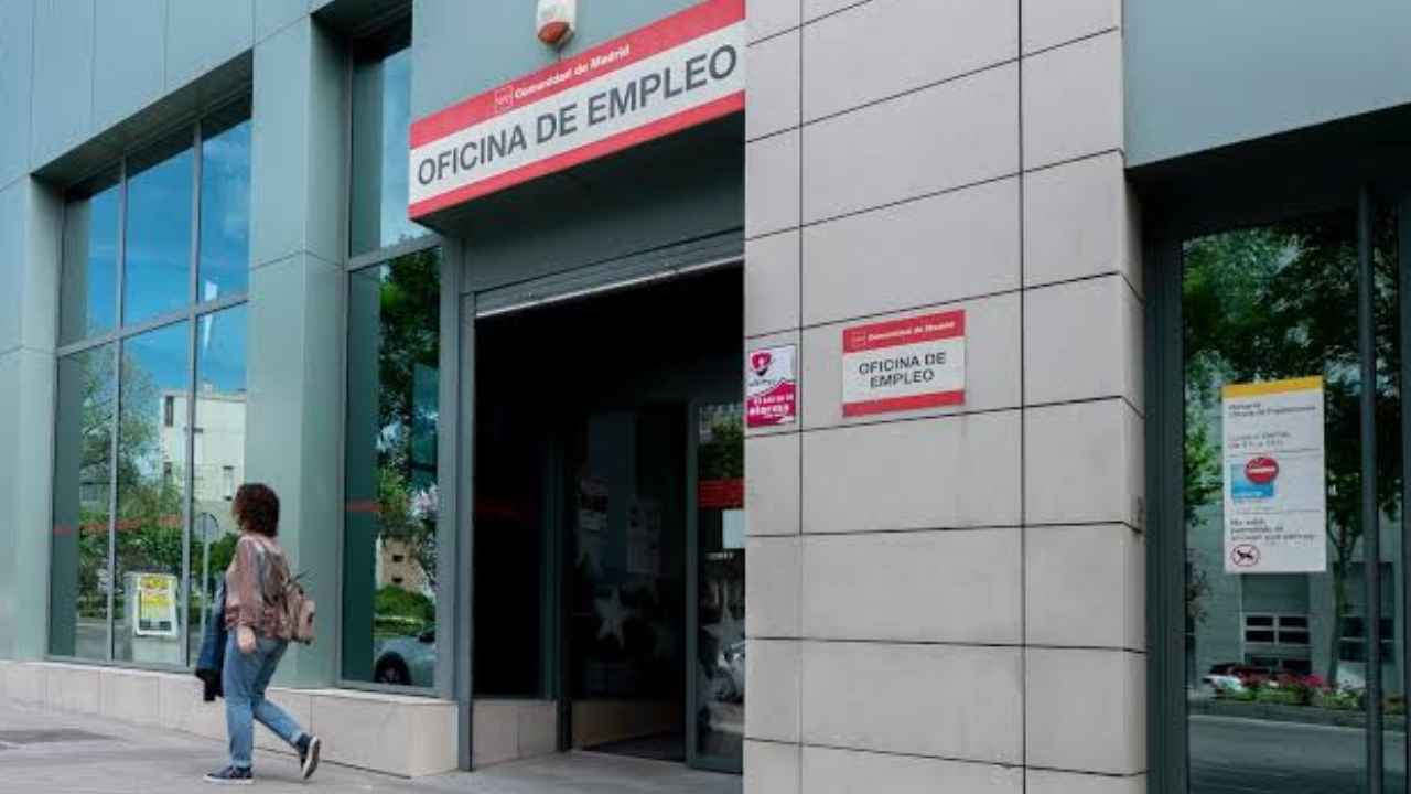 Mujer entrando en una oficina de empleo para solicitar información sobre el paro tras una baja voluntaria.