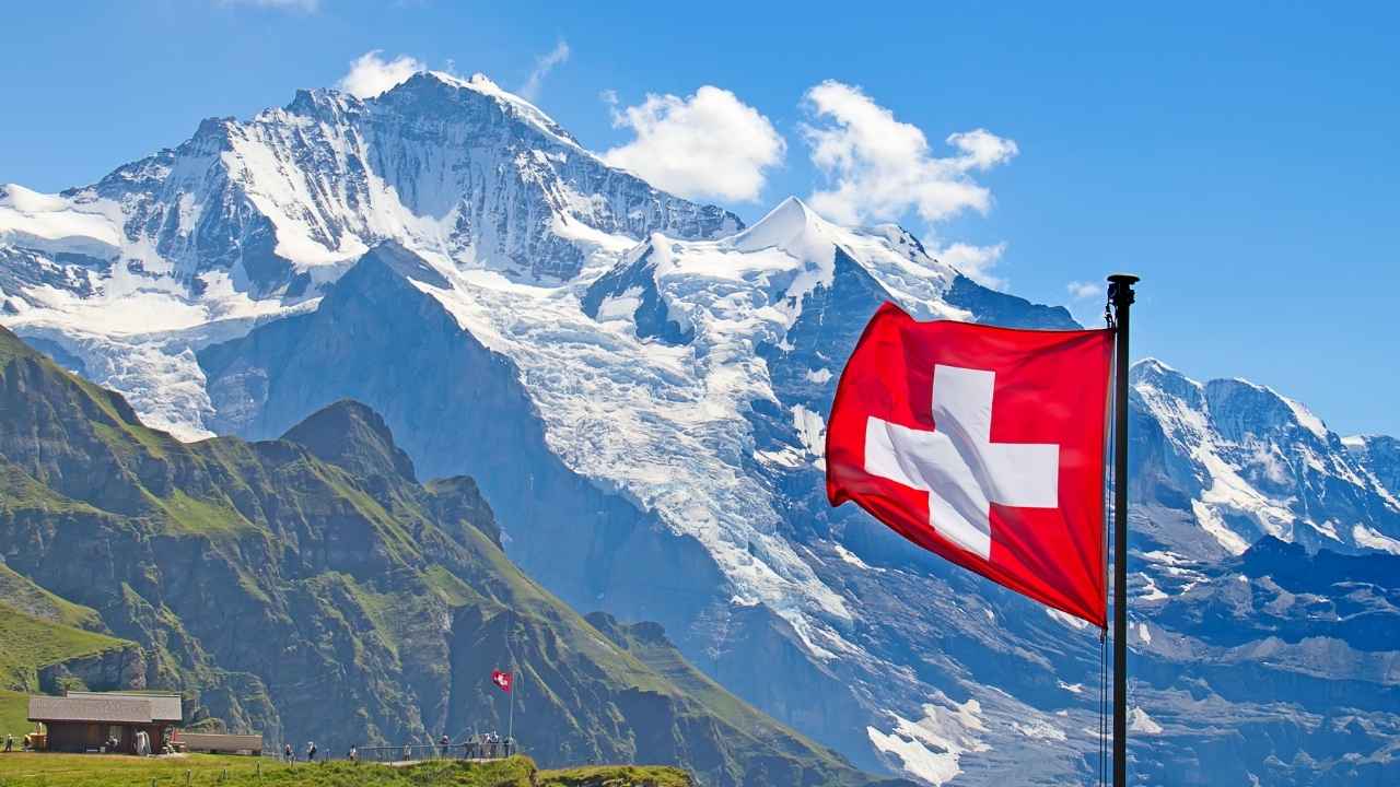 Bandera de Suiza frente a los Alpes para ilustrar los requisitos para trabajar en Suiza