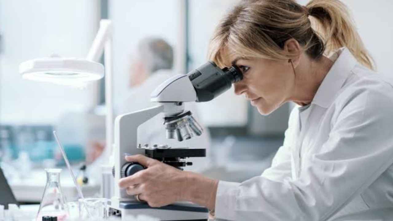 Investigadora observa una muestra con un microscopio en un laboratorio de investigación sanitaria